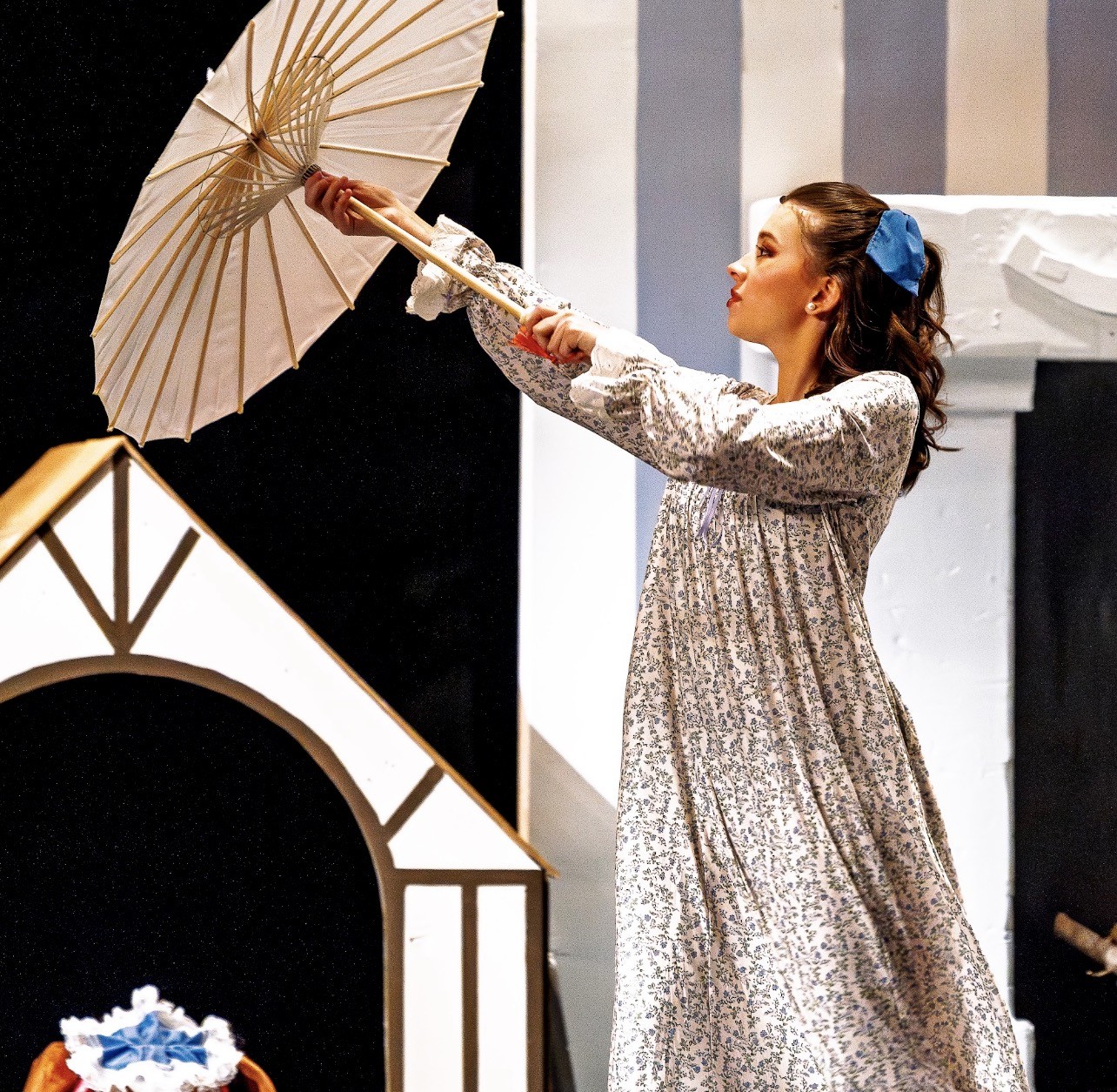 Tessa performing on stage with a parasol